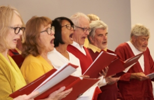 Men and women singing, dressed in yellow and red