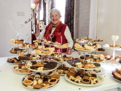 Lady smiling at a large array of cakes