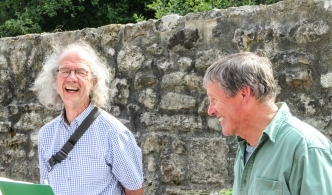 Two men, laughing, in front of a wall